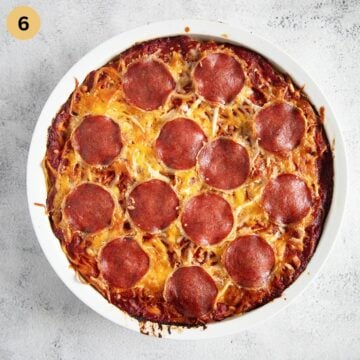 spaghetti pizza with salami baked in a round dish until golden and bubbly.