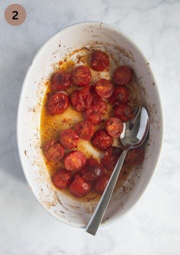 roasted tomatoes in a small baking dish with a spoon in it.