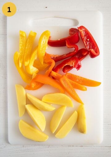 sliced potatoes and colorful peppers on a cutting board.