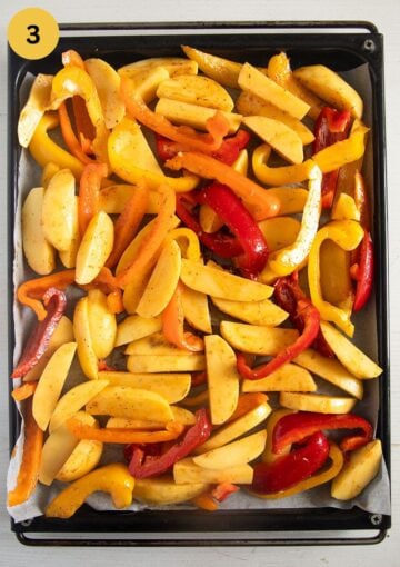 sliced potatoes and bell peppers on a baking sheet before roasting.
