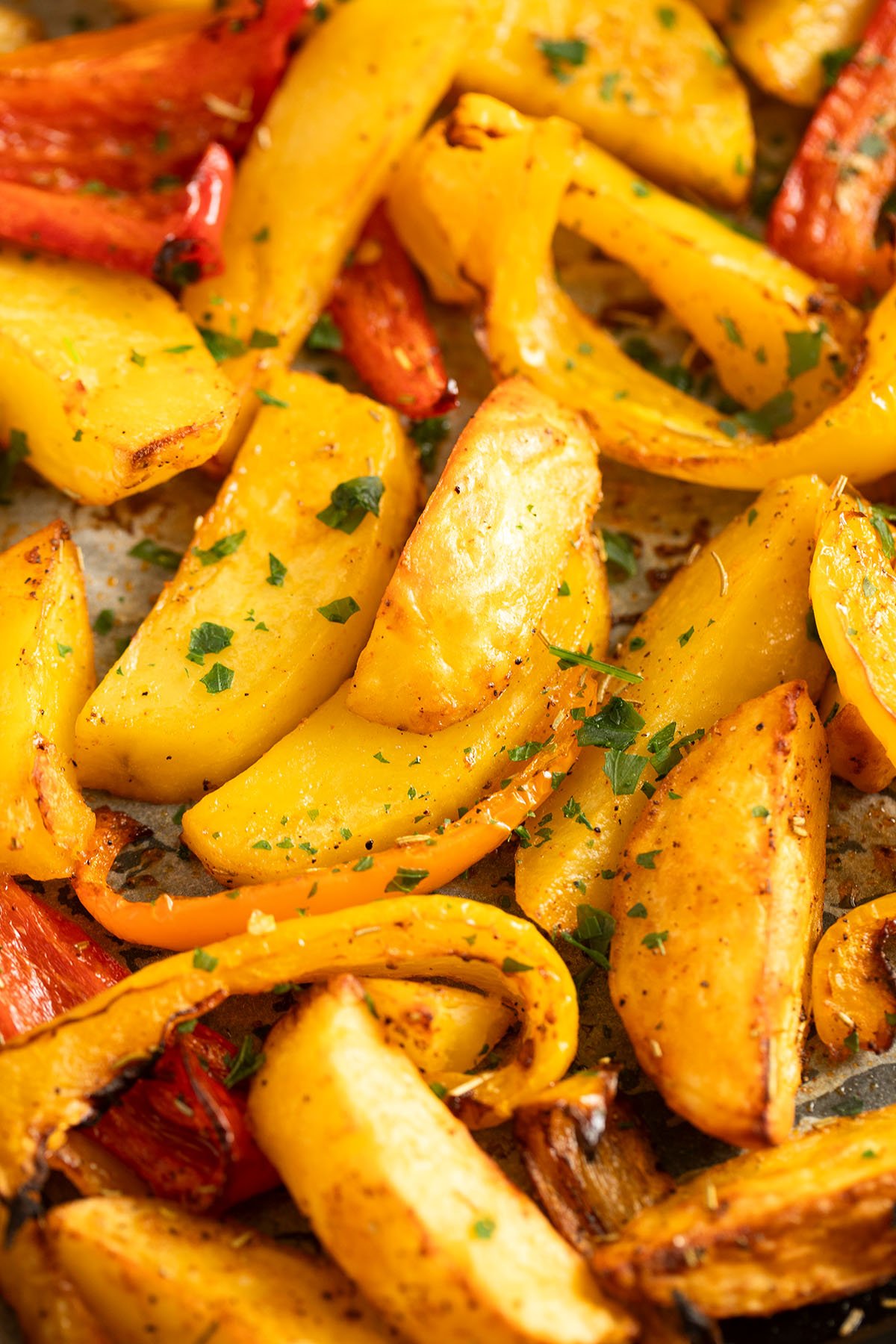 golden and tender potato wedges and peppers strips on a baking tray.