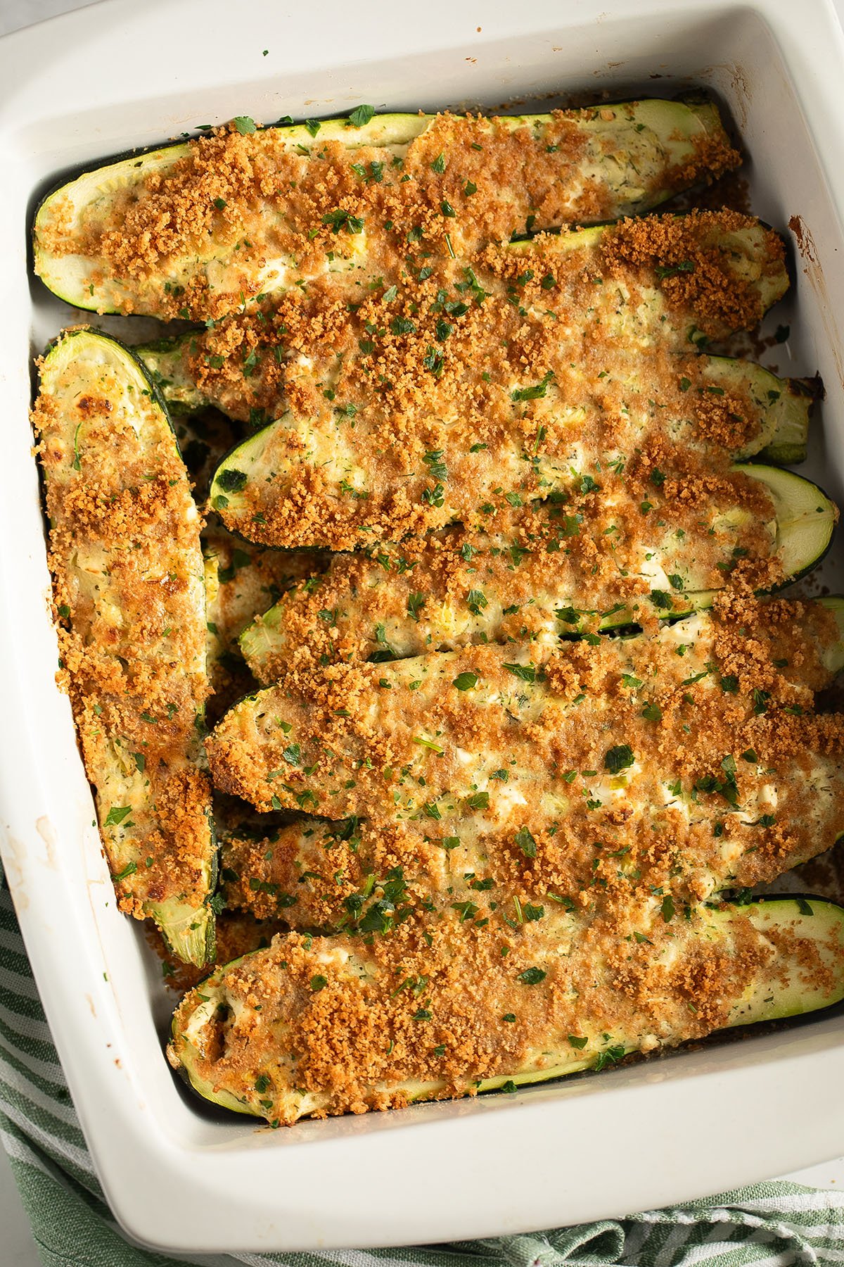 zucchini stuffed with feta and topped with golden baked breadcrumbs in a baking dish.