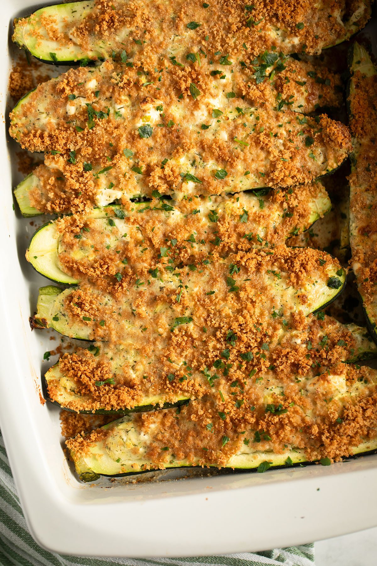 many zucchini boats stuffed with feta cheese and topped with golden breadcrumbs.