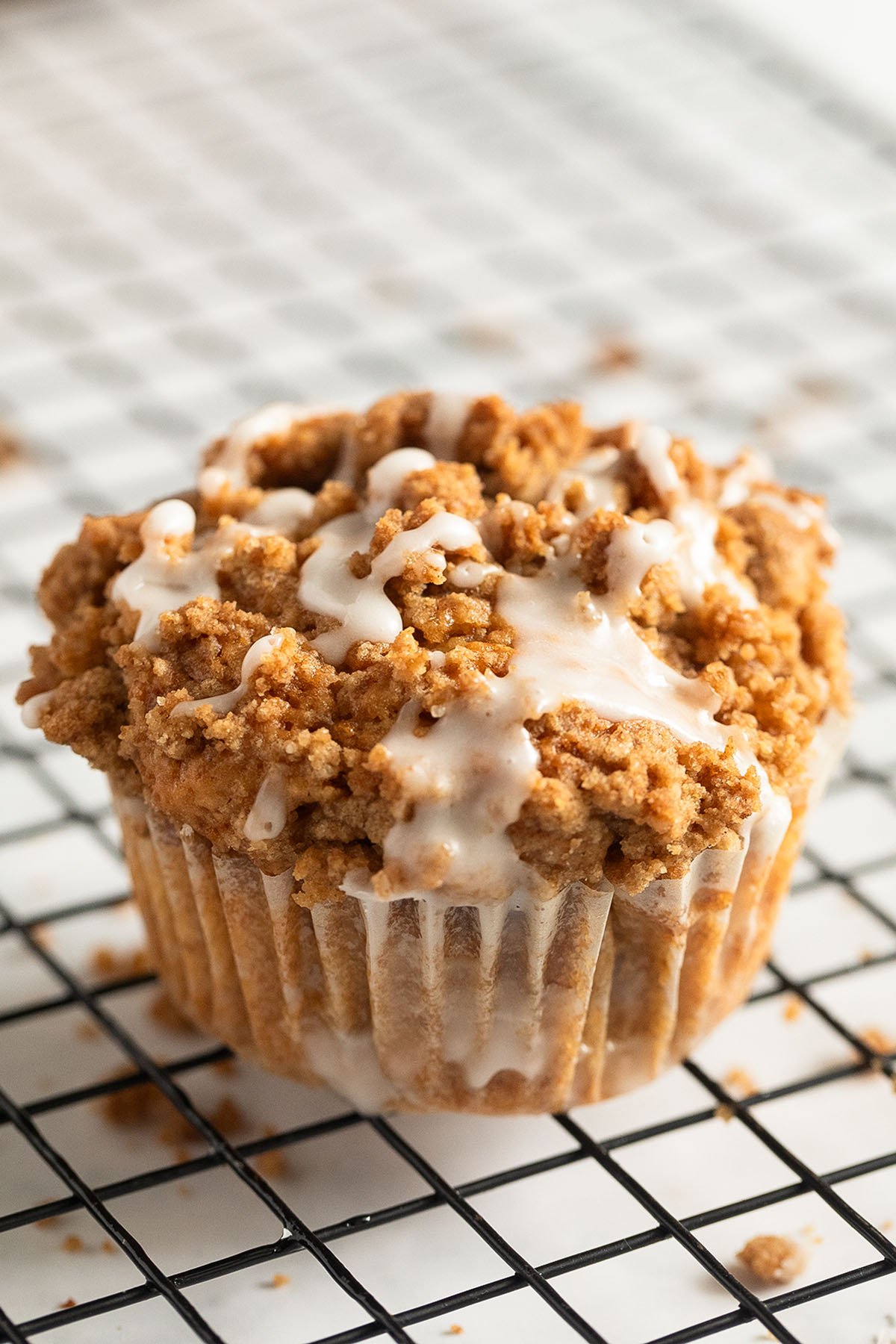 one large apple streusel muffins drizzled with lemon glaze on a wire rack.