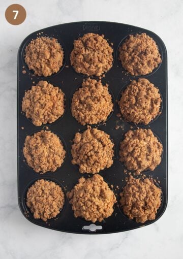freshly baked apple streusel muffins in a muffin pan.