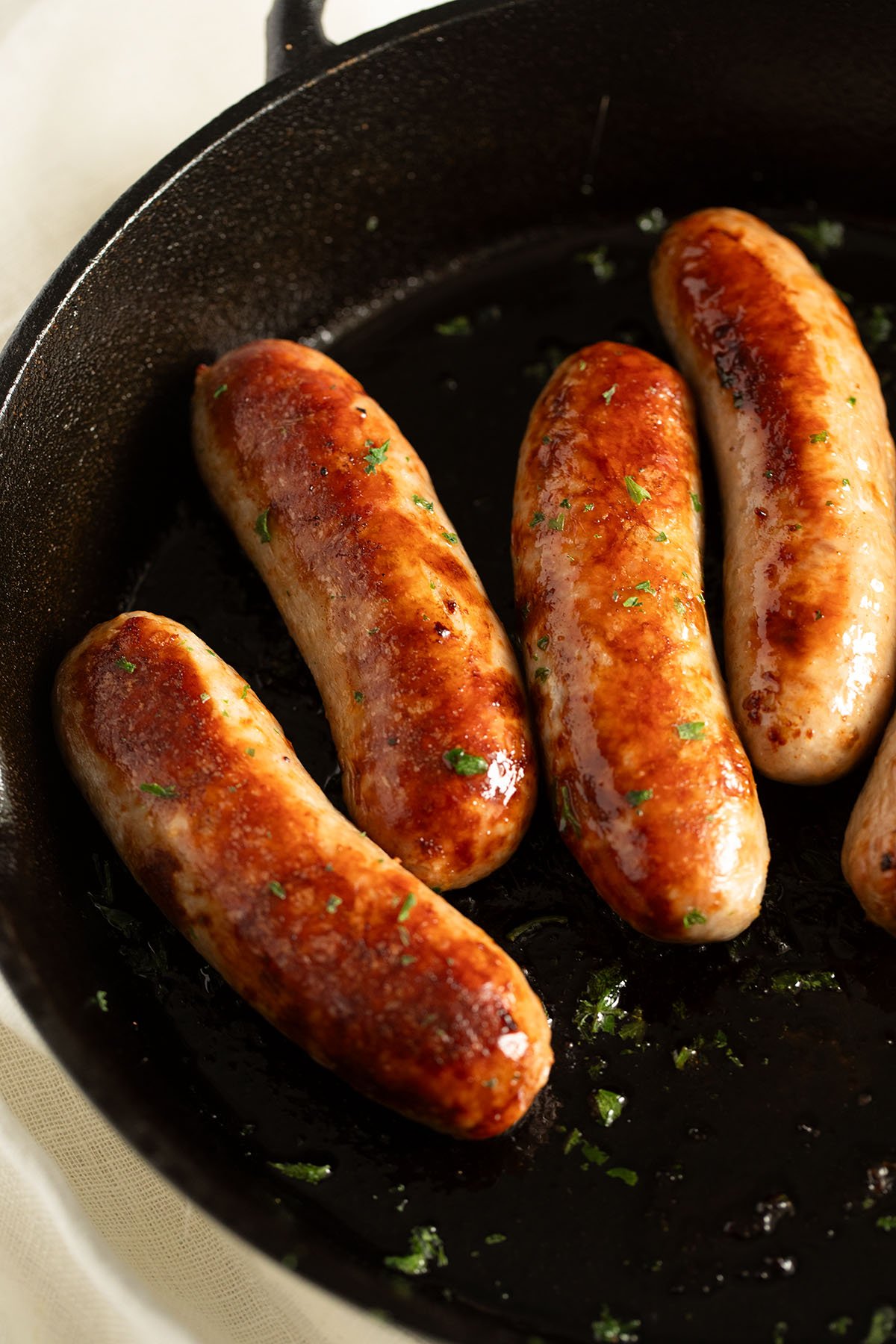 four baked sausages in a skillet.