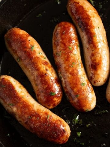golden oven-baked italian sausages in a cast iron skillet.