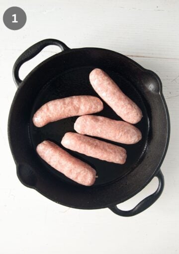 raw sausage links in a skillet before baking.