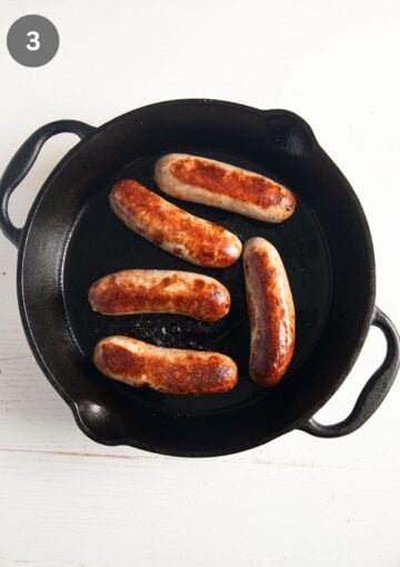 five baked sausages in a skillet.