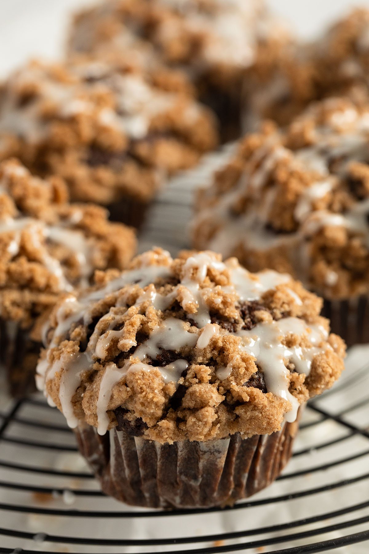 many pumpkin muffins with streusels on top on a wire rack.