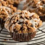 pumpkin muffin with streusel topping and drizzled with lemon glaze on a wire rack.