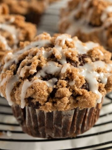 pumpkin muffin with streusel topping and drizzled with lemon glaze on a wire rack.