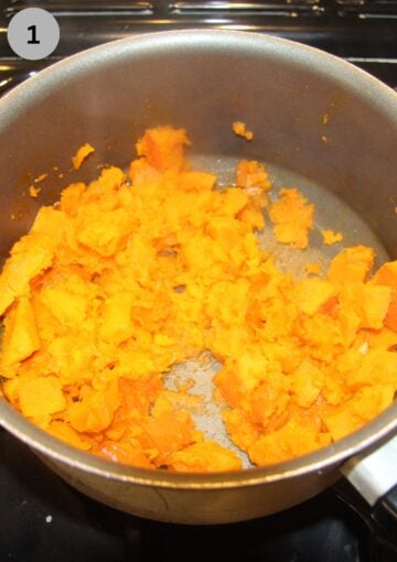 cubed pumpkin cooking in a small saucepan.