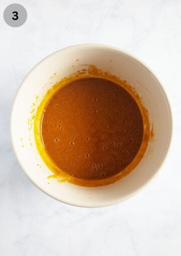 orange-colored pumpkin batter mixture for muffins in a bowl.