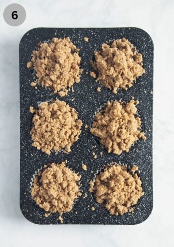 six freshly baked pumpkin streusel muffins in a muffin pan.