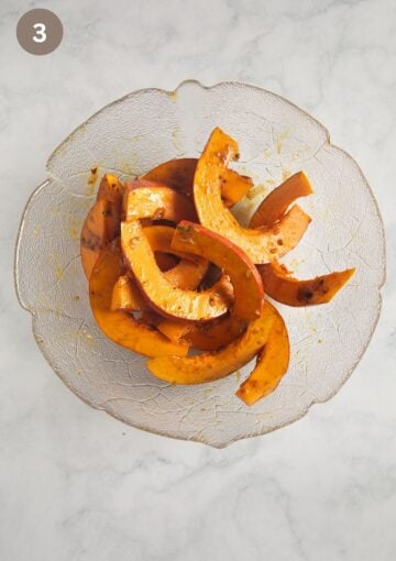 raw pumpkin slices coated with honey, oil and spice mixture in a bowl.