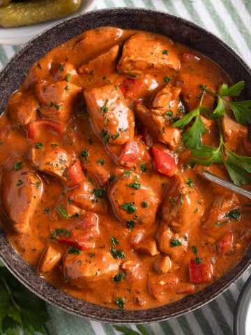 creamy turkey paprika with peppers in a large bowl with a spoon in it.
