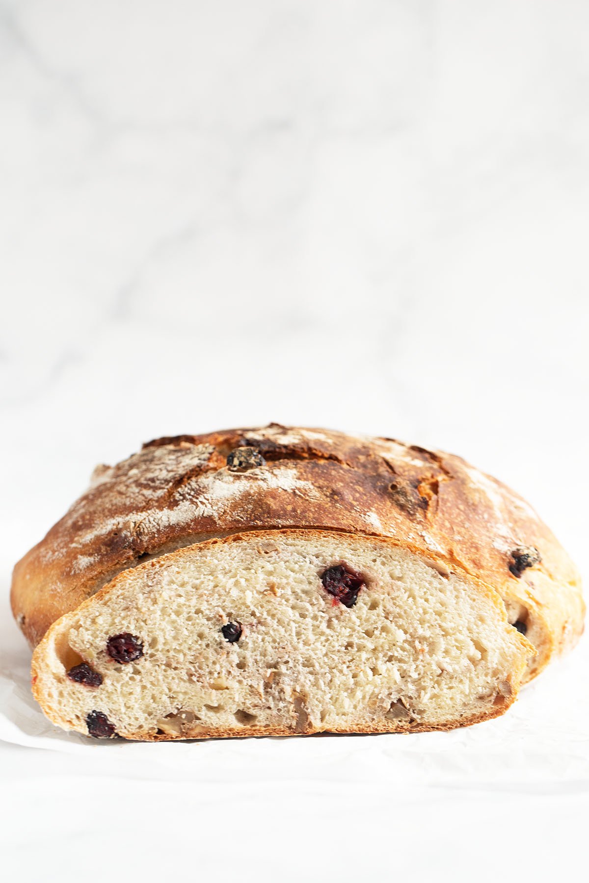 cut loaf of bread showing the walnuts and cranberries inside.