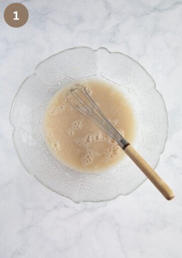 dissolving yeast in water by stirring it with a small whisk.