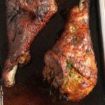 two golden brown baked turkey drumsticks close up.