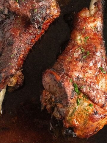 two golden brown baked turkey drumsticks close up.