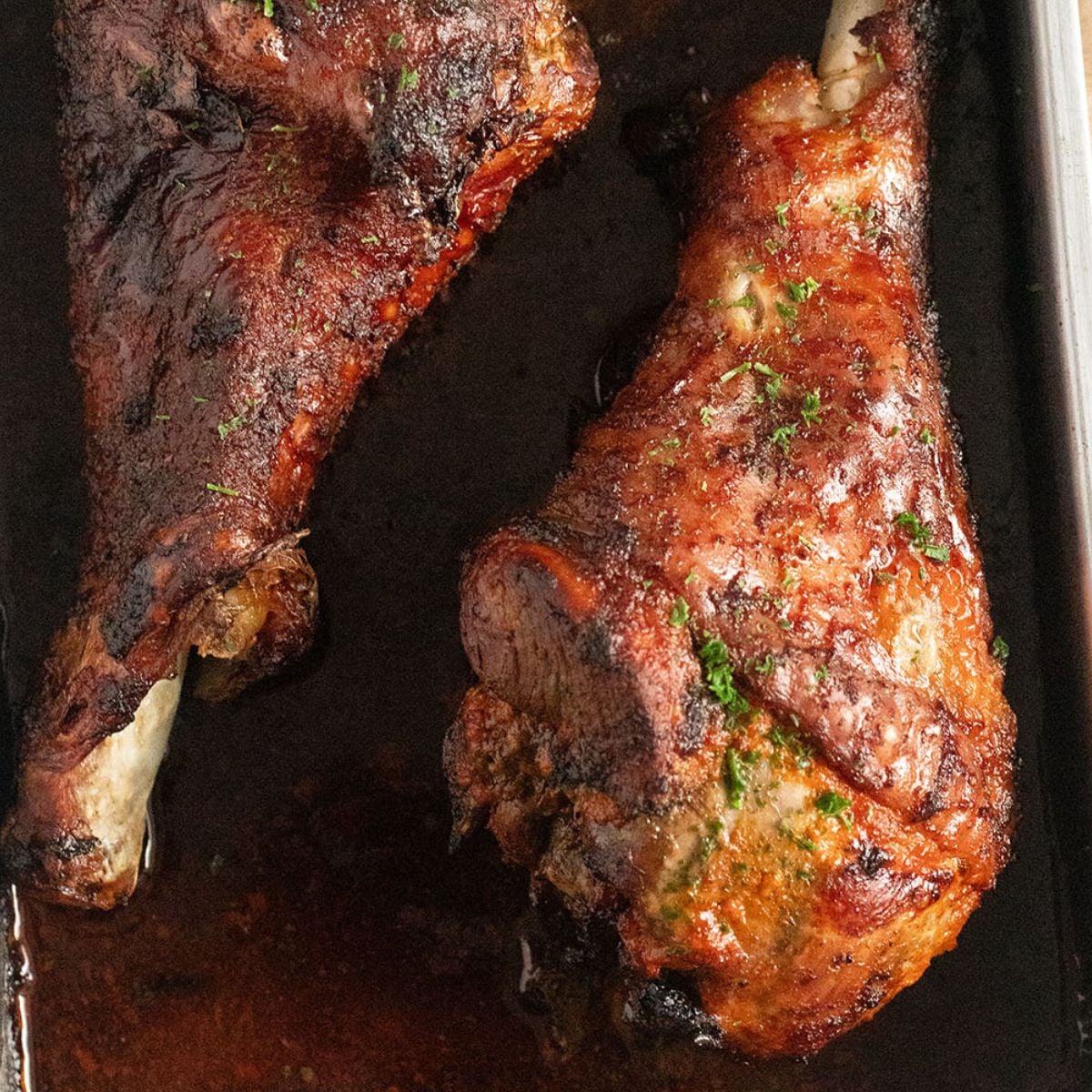two golden brown baked turkey drumsticks close up.