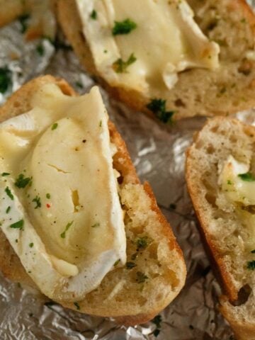brie baguette sprinkled with parsley on a piece of aluminum foil.