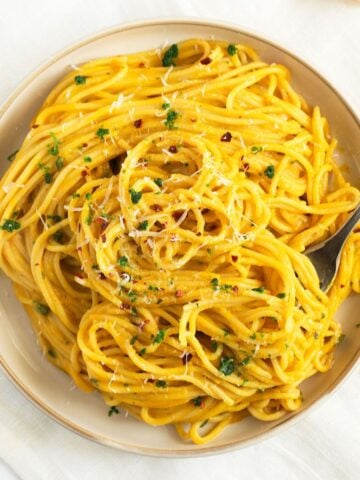 butternut squash pasta sauce on a plate with a fork stuck into it.