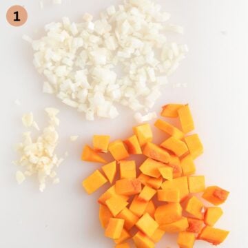 chopped onions, garlic and butternut squash for making pasta sauce on a cutting board.