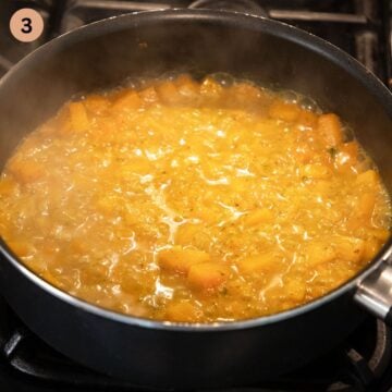 simmering butternut squash cubes to make pasta sauce in a sauce.
