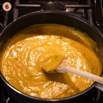 stirring smooth butternut sauce with a wooden spoon in a saucepan.
