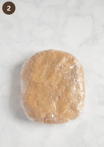 shortbread dough shaped into a rectangle and wrapped in plastic wrap.