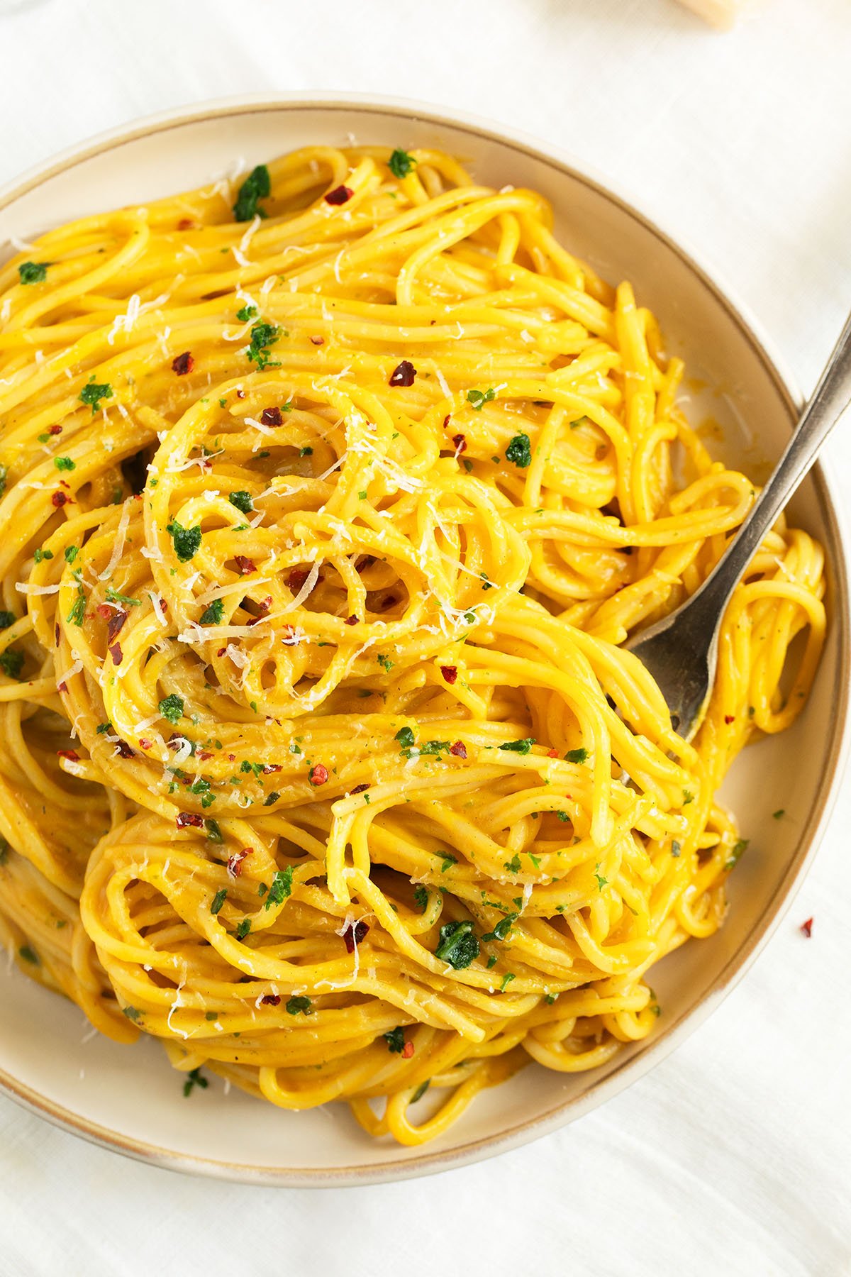 tangled spaghetti mixed with smooth butternut squash pasta sauce on a plate.