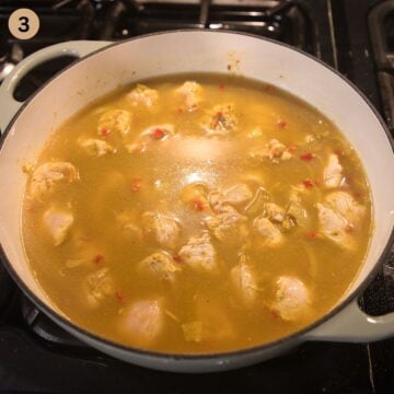 adding stock to chicken pieces to make curry in a pot.
