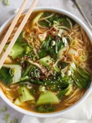 asian chicken noodles soup in a bowl with two chop sticks on top of it.