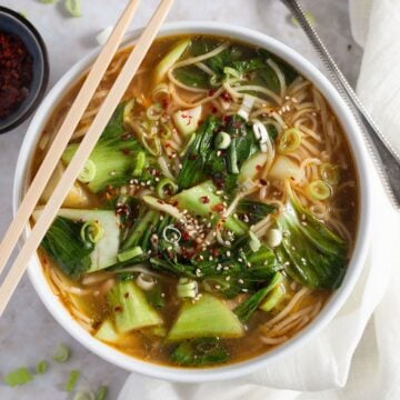 asian chicken noodles soup in a bowl with two chop sticks on top of it.