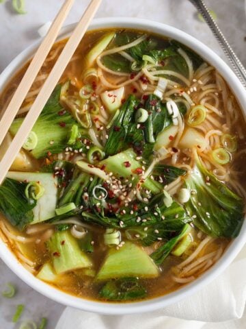 asian chicken noodles soup in a bowl with two chop sticks on top of it.