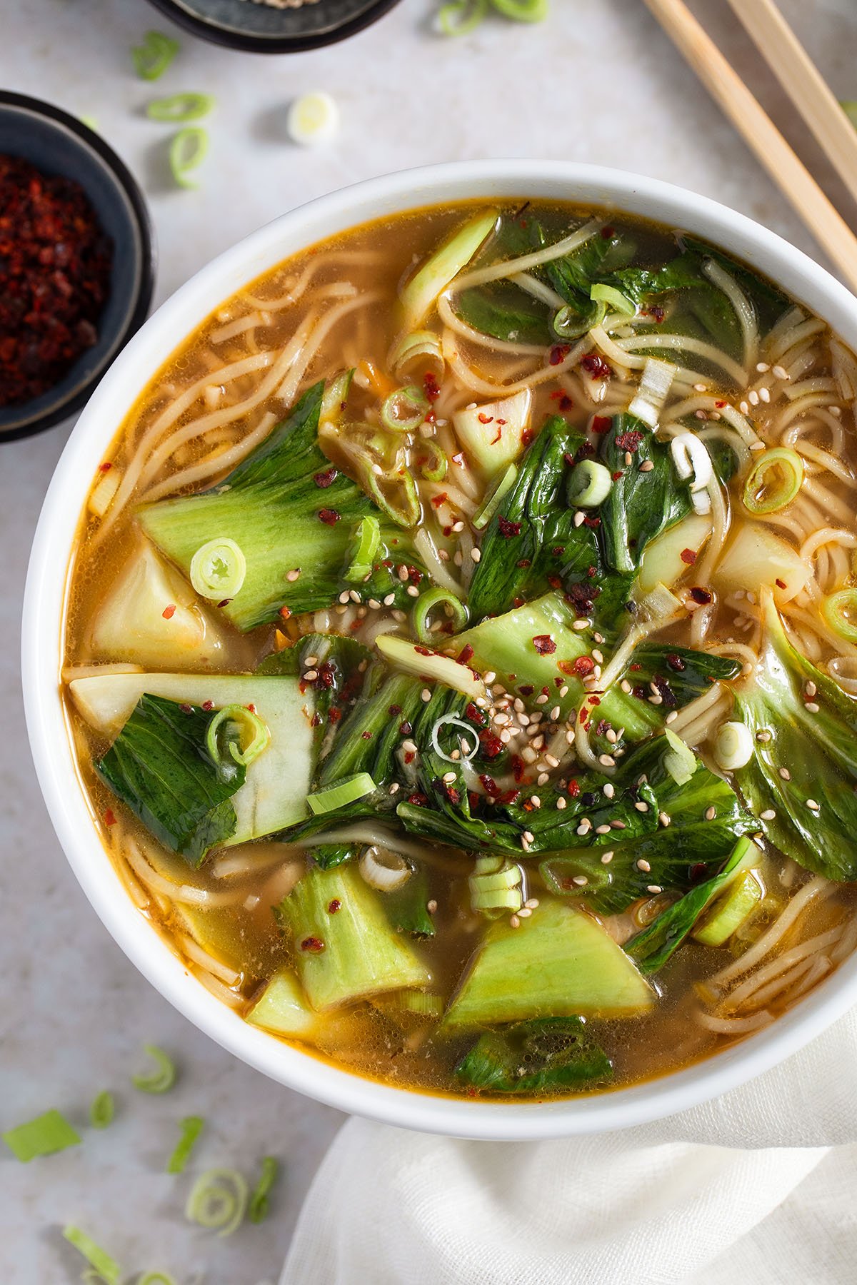 chicken noodle soup asian style in a bowl with small bowl and chop sticks around it.