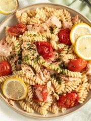 salmon pasta without cream garnished with lemon slices on a large plate.