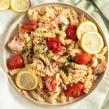 salmon pasta without cream garnished with lemon slices on a large plate.