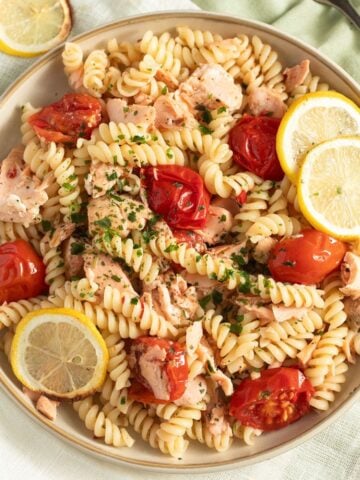 salmon pasta without cream garnished with lemon slices on a large plate.