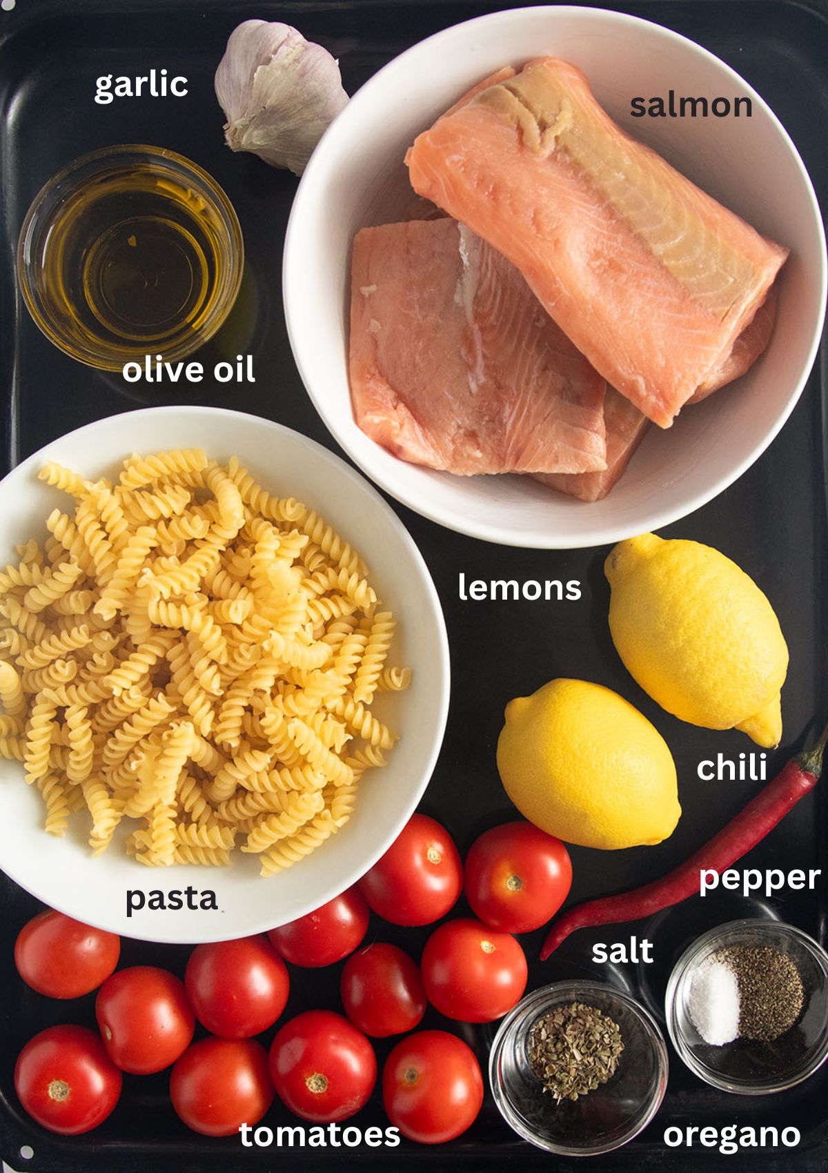 labeled ingredients for making pasta with salmon, small tomatoes, olive oil, garlic, chili.