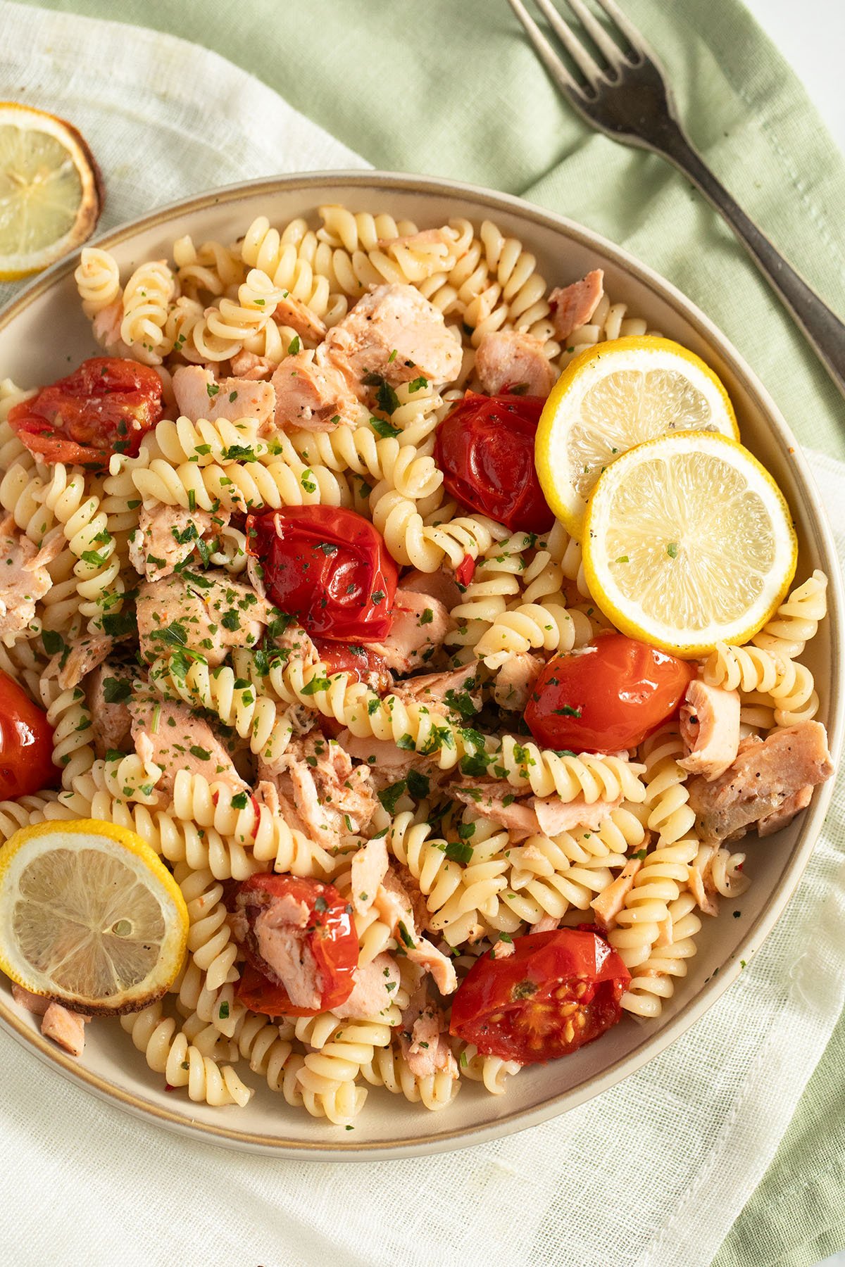 plate with no cream salmon pasta with tomatoes and lemon.