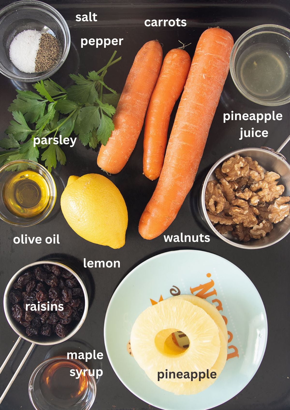 labeled ingredients for making a salad with raw carrots, pineapple, raisins, parsley and lemon maple syrup dressing.