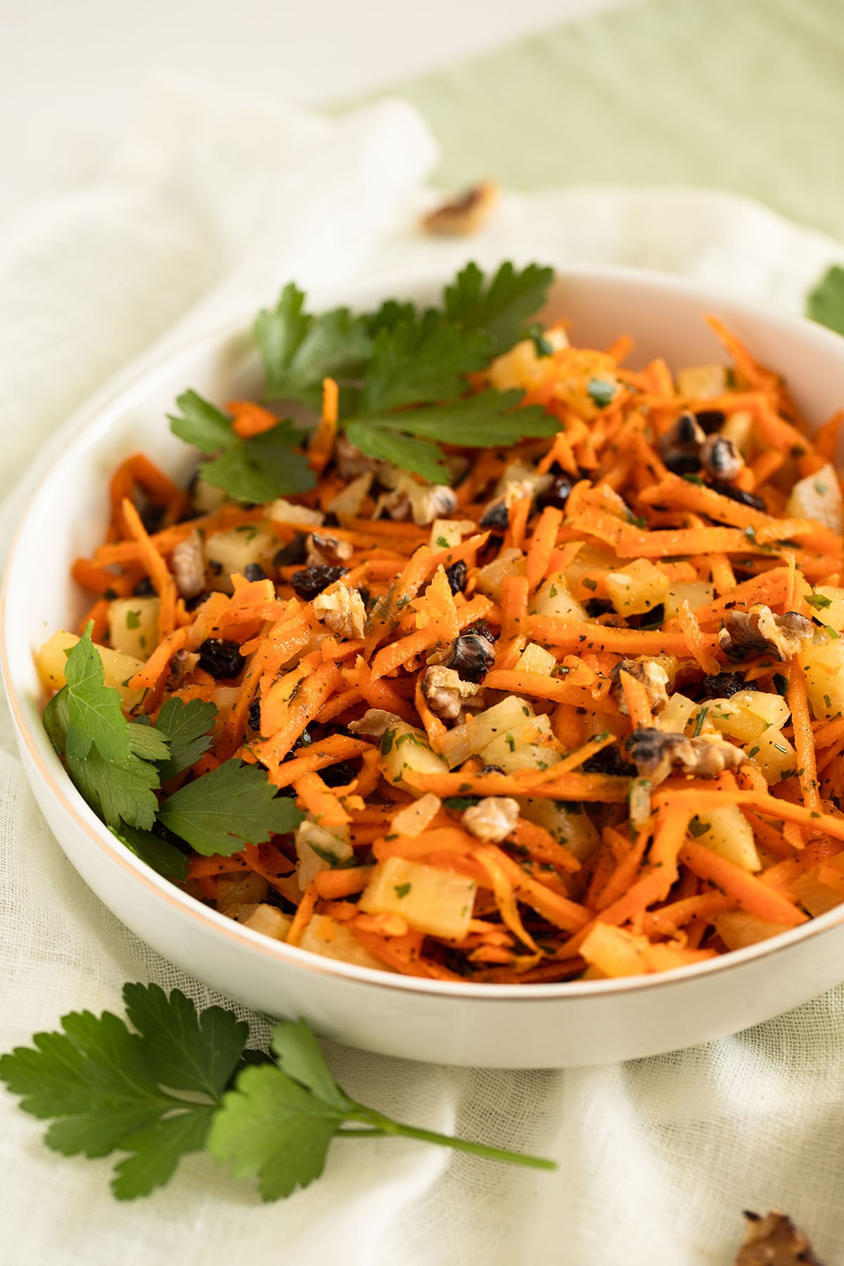 carrot and pineapple salad with raisins, walnuts and parsley in a bowl.