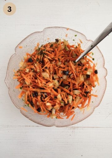 mixing grated carrots, chopped pineapple, raisins with the dressing in a bowl with a spoon.