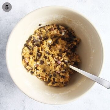 adding chopped mini eggs and walnuts to cookie bar dough in a bowl.