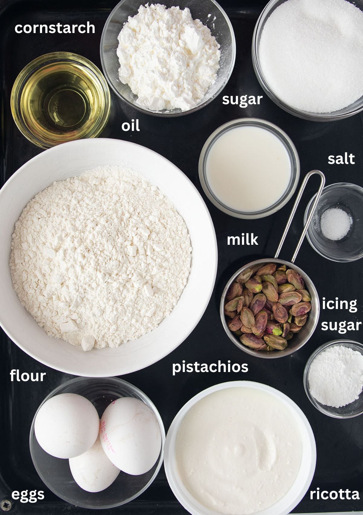 labeled ingredients for making cake with ricotta, pistachios, flour, eggs, cornstarch, oil, sugar.