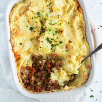 pork shepherd's pie showing a bit of the meat filling in a baking dish.