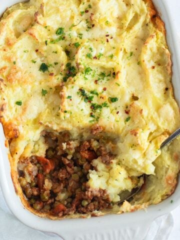 pork shepherd's pie showing a bit of the meat filling in a baking dish.